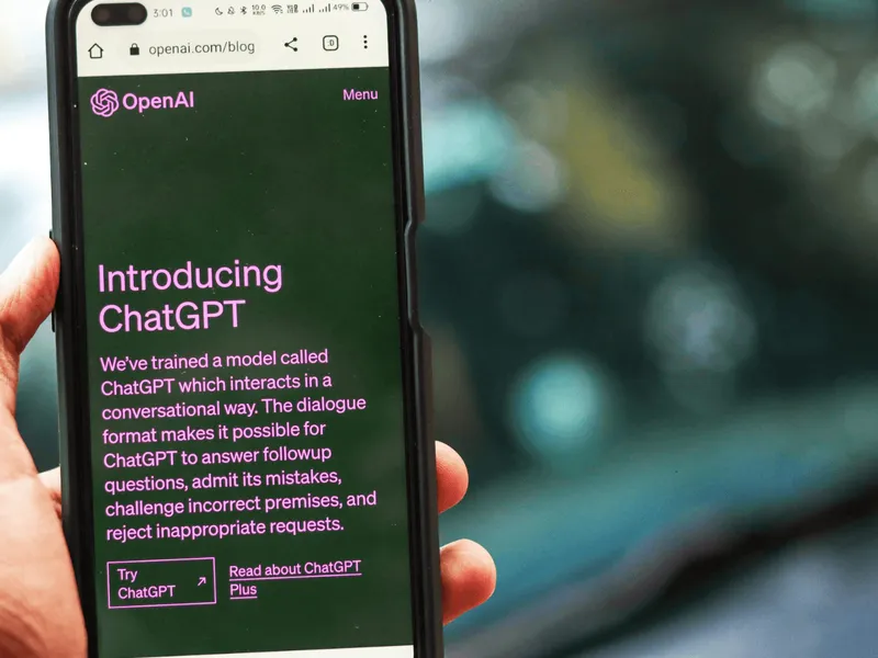 Una mano sostiene un teléfono con la página de OpenAI que anuncia ChatGPT
