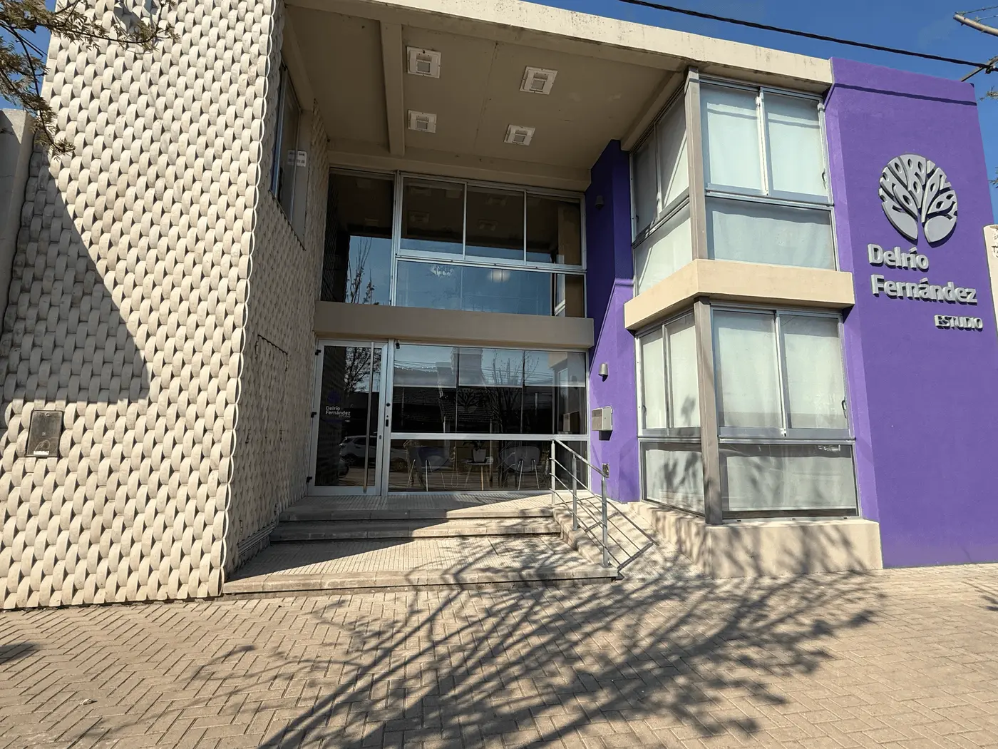 Frente del edificio del estudio, con su fachada violeta y el logo del árbol sobre la entrada