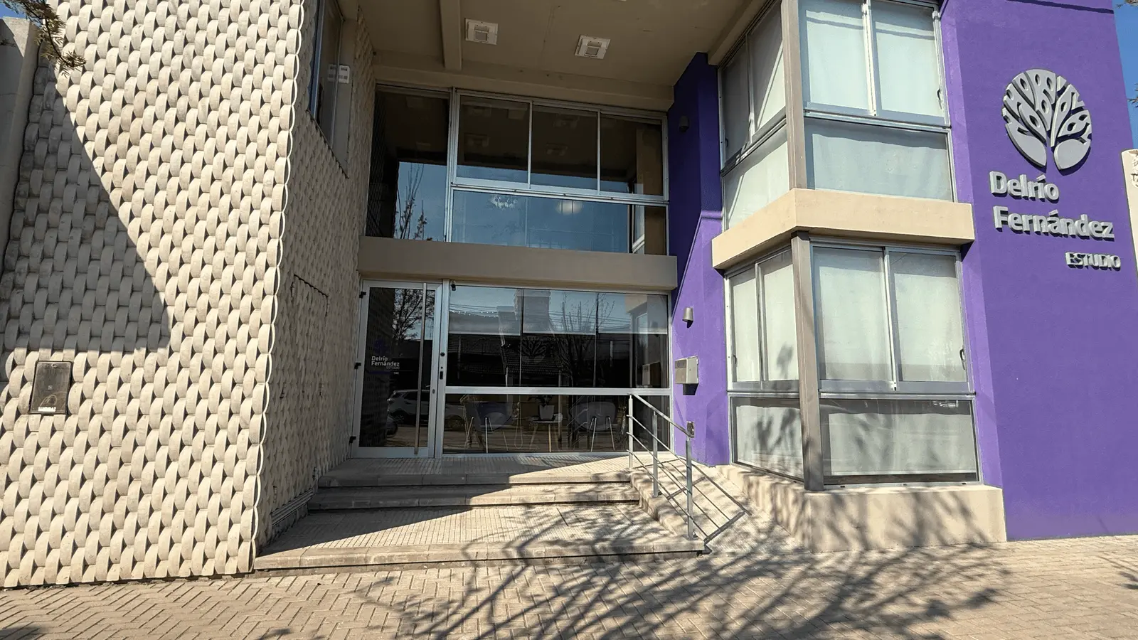 Frente del edificio del estudio, con su fachada violeta y el logo del árbol sobre la entrada